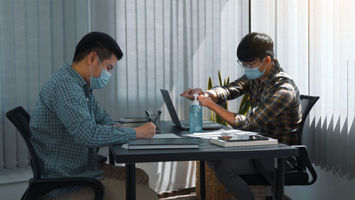 Business persons wearing mask sitting at office