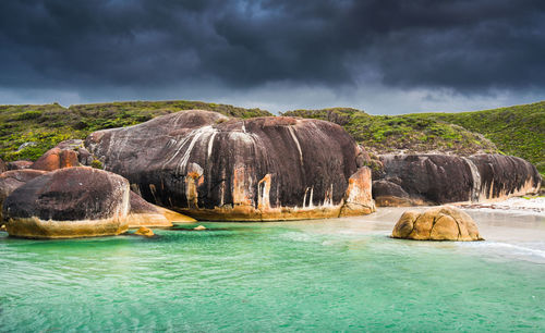 Rocks in sea against cloudy sky