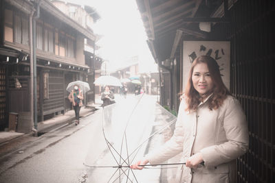 Portrait of young woman standing on street in city