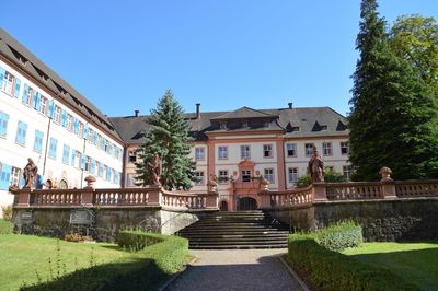 Footpath amidst buildings against blue sky