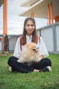 Portrait of woman with dog sitting on grass