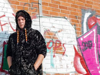 Fashionable mature man standing against graffiti wall