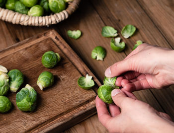 Cropped image of person holding vegetables on cutting board