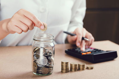 Cropped image of hand holding glass jar on table