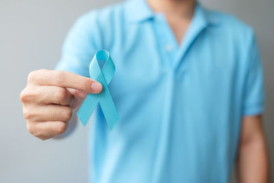 Close-up of man holding hands over blue background