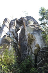 Low angle view of rock formation amidst trees against sky