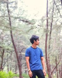 Full length of young man looking away in forest