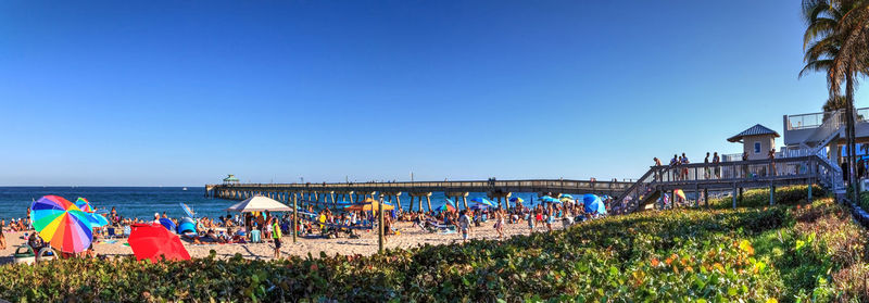 Crowded sands of deerfield beach near the pier with unrecognizable faces in deerfield, florida