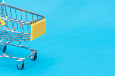 Close-up of shopping cart against blue background