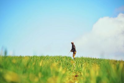 Side view of farmer standing on agricultural field against sky