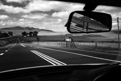 Road against cloudy sky seen through car windshield