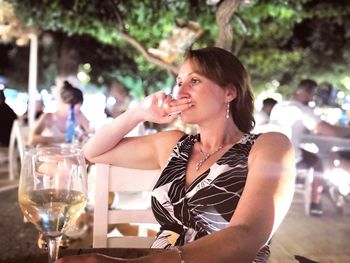 Thoughtful woman having wine at outdoor restaurant during night