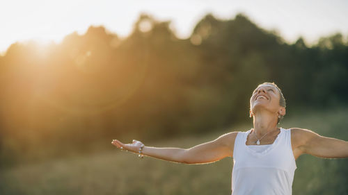 Woman with arms outstretched standing outdoors