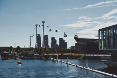 Sailboats moored on river by city against sky