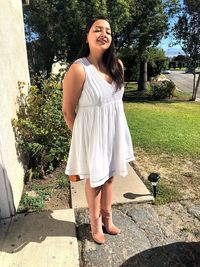 Smiling young woman standing against plants