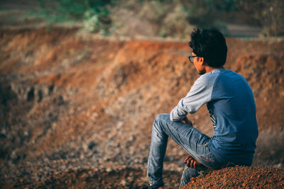 Side view of man sitting on land