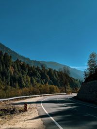 Road by trees against blue sky