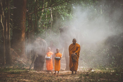 Rear view of people standing in forest