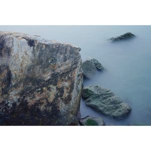 Rocks by sea against clear sky