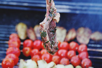 Close-up of a marinated lamb rack getting ready to go on the grill together with the tomatoes 