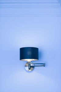 Low angle view of electric lamp against blue background