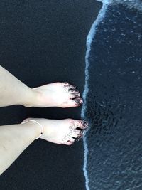 Low section of woman standing at beach