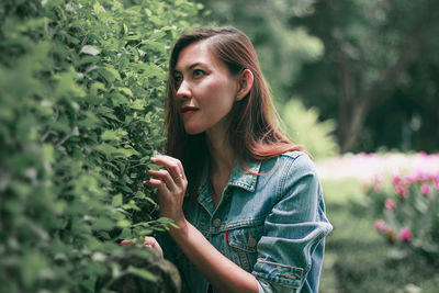 Portrait of young woman against plants