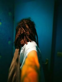 Side view of woman with dreadlocks standing by wall