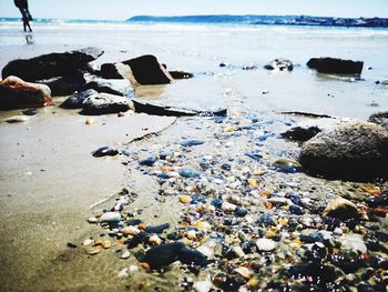 Surface level of stones on beach against sky