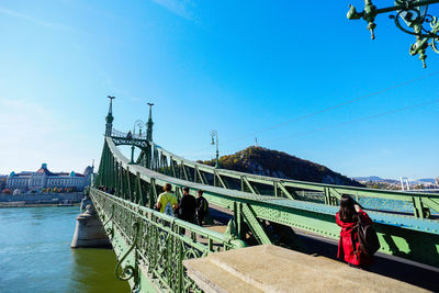 People at liberty bridge over danube river against sky