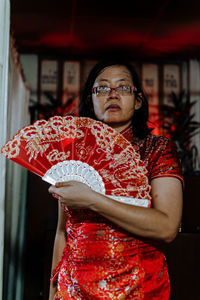 Portrait of woman standing against red wall