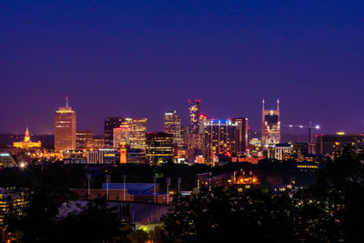 Illuminated buildings against clear sky at night