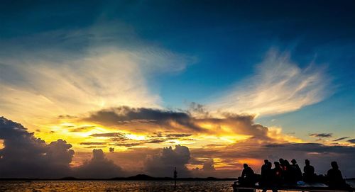 Silhouette people on beach against sky during sunset