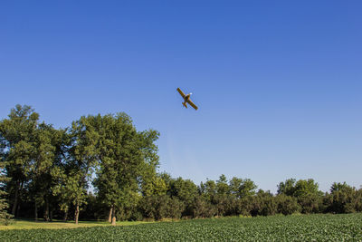 Low angle view of airplane flying against clear blue sky