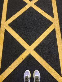 Low section of man standing on road marking