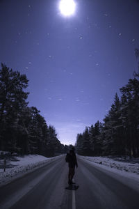 Rear view of person on road against sky at night