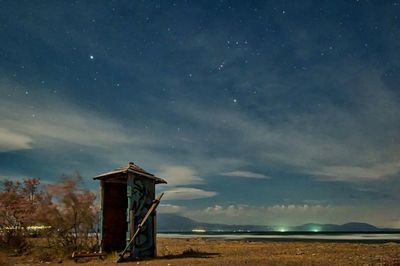 Lifeguard hut on beach against sky at night