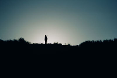 Silhouette man standing on field against clear sky