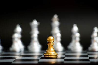 Close-up of chess pieces on board against black background