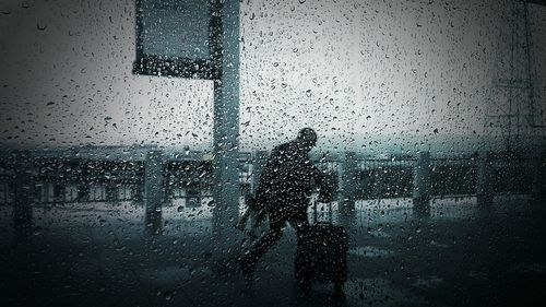 Man seen through wet glass window in rainy season