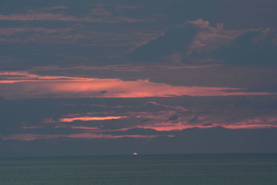 Scenic view of sea against dramatic sky during sunset