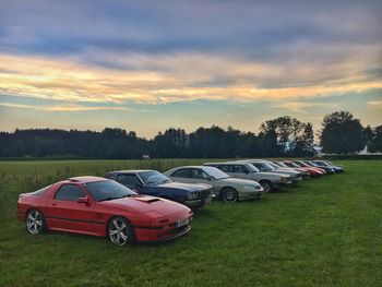 Cars on field against sky during sunset