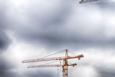 Low angle view of cranes against sky