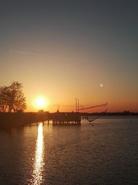 Silhouette bridge over river against sky during sunset