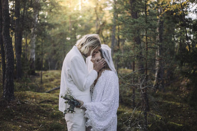 Newly married couple kissing in forest on wedding day