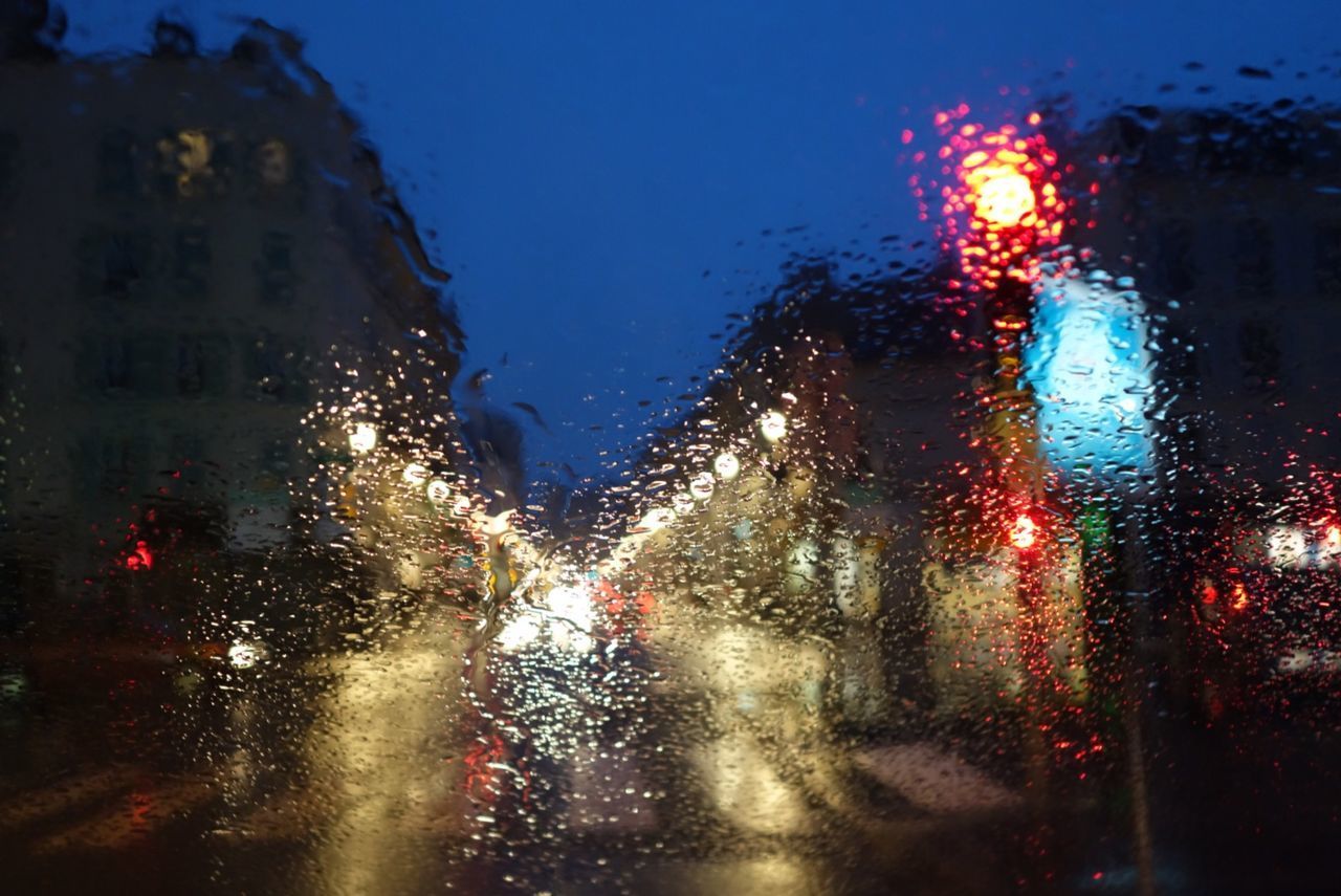 ILLUMINATED CITY SEEN THROUGH WET WINDOW