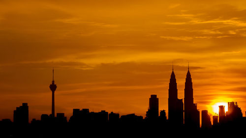 Silhouette of cityscape against orange sky during sunset