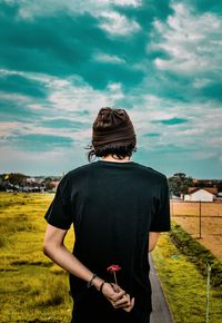 Rear view of woman standing on field against sky