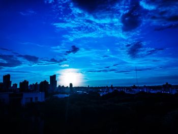 Silhouette buildings against sky at sunset