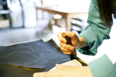 Cropped image of shoemaker working on table in workshop